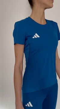 Kék atlétikai póló rövid ujjakkal és kerek nyakkivágással, fehér, bal mellkason átlós csíkokkal és testhez simuló szabással.