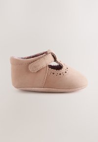 Chaussure bébé rose douce avec une bride Velcro et des perforations en forme de cœur, montrée de profil sur un fond clair uni.