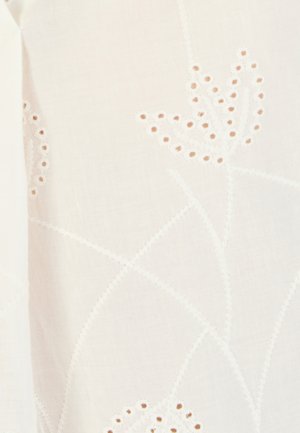 Tejido blanco delicado con patrones florales bordados y pequeños recortes circulares que forman elegantes diseños de flores.