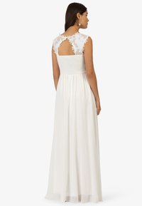 Weißes Maxikleid mit einem gerafften Oberteil, Spitzenkapellenärmeln und einem offenen Rückendetail. Fließender, transparenter Stoff für ein leichtes Erscheinungsbild.