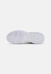 Talpa de adidasi alba cu un model în zigzag, elemente circulare de tracțiune și un logo Nike proeminent. Material din cauciuc texturat.