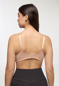 Reggiseno nudo con tessuto liscio e testurizzato, spalline in satin regolabili e chiusura a ganci sul retro, abbinato a un pantaloncino nero a vita alta.