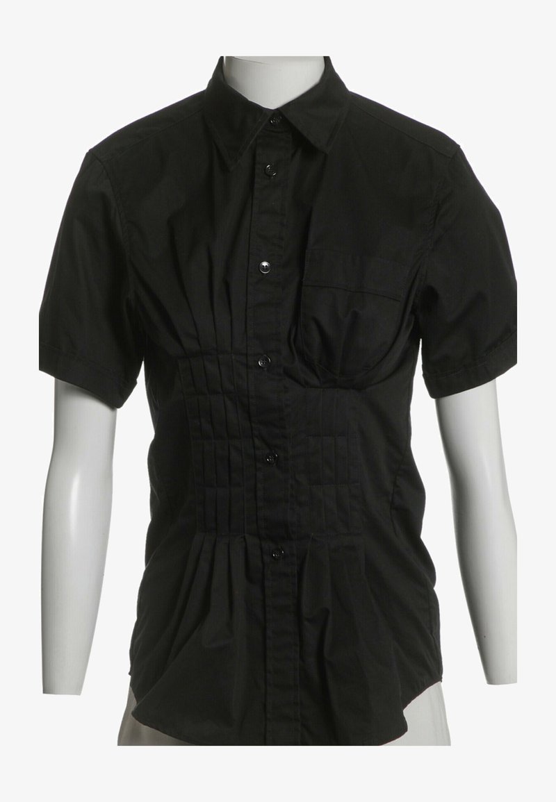 Chemise noire à manches courtes avec boutons, col, poche poitrine avant et plis froncés sur le devant et les côtés, présentée sur un mannequin blanc.