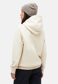 Cremefarvet hoodie med snor i hætten, ribbede manchetter og kant, lavet af blødt stof. Båret med en beige strikket beanie.