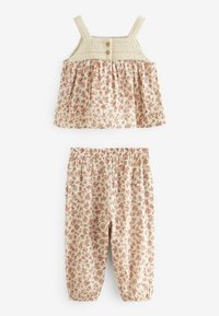 Blommig tvådelad outfit med en krämfärgad tanktopp med vävda axelband och två knappdetaljer; matchande byxor med elastisk midja och blommönster.