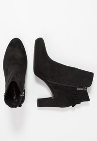 Černé semišové kotníkové boty s elegantní špičatou špičkou, bočním zipem a volánkovým detailem na vnějším švu. Mají vysoký, robustní podpatek.