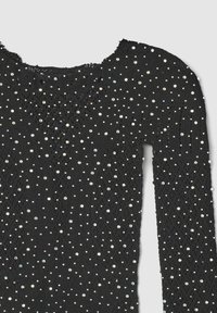Maglietta nera in maglia con scollo a barca, decorata con numerosi paillettes iridescenti distribuite uniformemente su tutta la superficie.