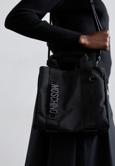 Sac à main noir en nylon avec des poignées courtes, arborant le logo "Moschino" en relief. Le design est simple, sans motifs ni accents visibles.