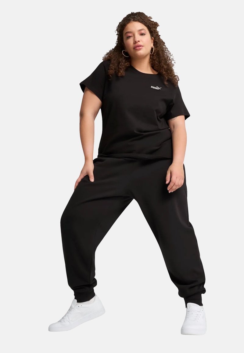 Sort atletisk tøj bestående af en løs t-shirt og matchende joggers, lavet af blødt stof, kombineret med hvide sneakers. Enkel design uden mønstre.