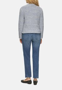 Blaue und weiße Tweedjacke, taillierter Schnitt, runder Ausschnitt, Rückansicht. Getragen mit geraden Jeans in Denim, fransigem Saum und schwarzen Ballerinas.