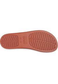 La semelle de la chaussure en caoutchouc rouge Crocs présente un motif de bande de roulement pour une meilleure adhérence, avec des rainures ovales et diagonales. Elle comprend des informations de taille près du talon.