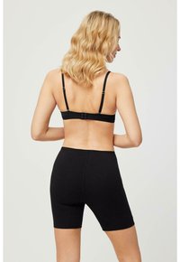 Sujetador negro con tirantes ajustables y cierre de gancho, combinado con pantalones cortos de ciclismo negros de cintura alta. Ambos están hechos de una tela suave y elástica.