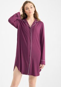 Camisa de noche de manga larga en burdeos profundo con ribetes blancos. Presenta un cierre de botones, un corte relajado y una abertura lateral para mayor comodidad.