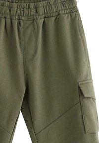 Khaki cargobroek met elastische tailleband. Voorzien van schuin lopende naden, zijzak en een gladde textuur. Geschikt voor casual wear.