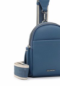 Blue leather crossbody bag with a textured finish, zip closure, front pocket, and patterned fabric strap featuring beige accents.