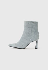 Stivaletto in denim con punta affusolata, color blu chiaro, e decorato con piccole borchie argentate. Presenta un tacco a spillo e un tessuto strutturato.