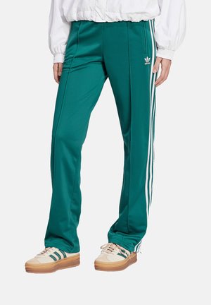 Gröna joggingsbyxor i smooth tyg med vita sidostriper och en broderad logotyp. Designade med en avsmalnande ben och elastisk midja.