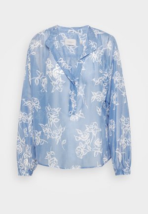 Blusa azul clara, transparente, com padrão floral branco, mangas longas e um ajuste ligeiramente descontraído. Apresenta um colarinho clássico e lapela de botões.