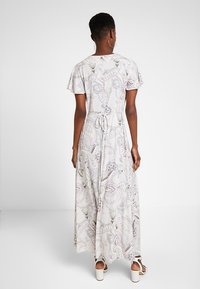 Maxi dress with short sleeves, light fabric, paisley pattern in pastel colors, tied waist, full-length design, and flared skirt.