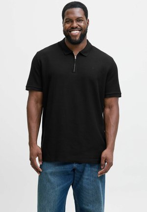 Black polo shirt with a half-zip collar, short sleeves, and a textured fabric, paired with blue loose-fitting jeans.