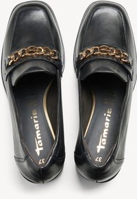 Chaussures en cuir noir avec un design à bout carré. Elles présentent un accent de chaîne dorée sur le dessus et une doublure intérieure lisse.