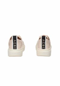Hellrosa Sneakers mit glatter Textur, weißen Sohlen und einem kontrastierenden schwarz-weißen Rückenteil mit Logo. Abgerundete Form.