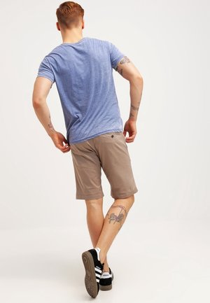 Maglietta da uomo blu melange a maniche corte, abbinata a pantaloncini color cuoio. Scarpe da ginnastica nere e bianche con suola texturizzata e dettagli con logo.