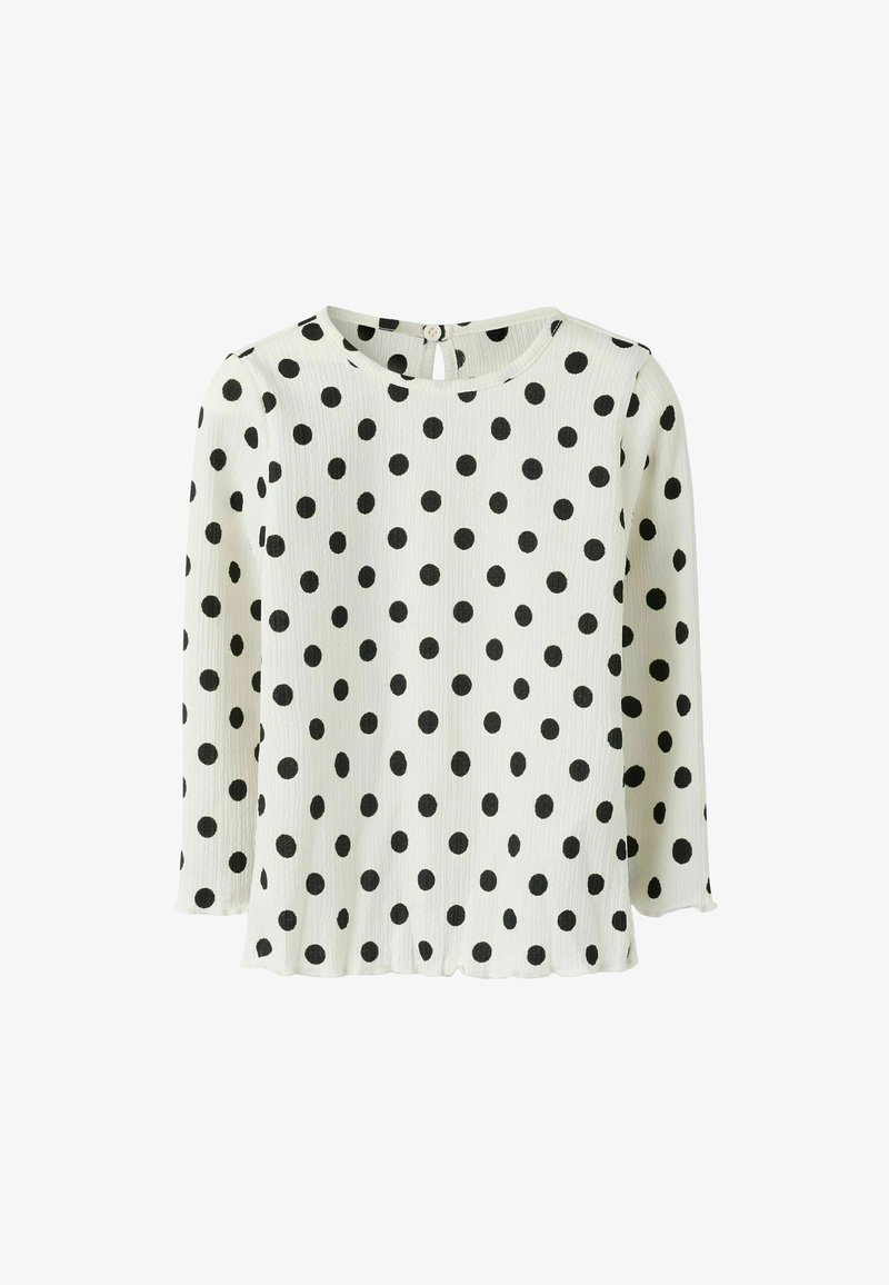 Lunares negros sobre un fondo blanco, de manga larga, textura acanalada, escote redondo con un pequeño botón y abertura en forma de llavero en la parte posterior.