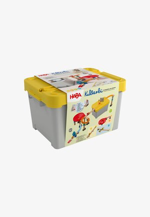 Szare i żółte plastikowe pudełko do przechowywania z opakowaniem zestawu zabawek toru kulkowego HABA Kullerbü owiniętym wokół niego.