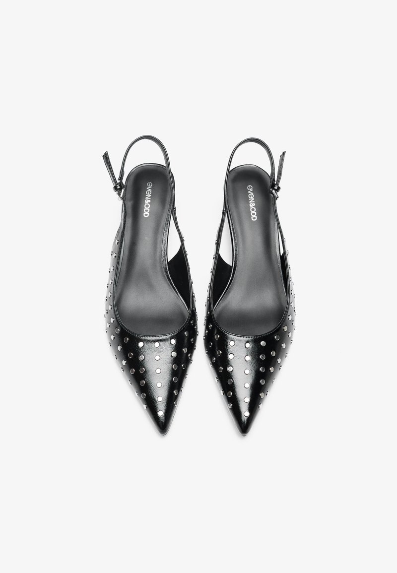 Talons slingback noires avec bouts pointus, fabriquées en matériau brillant, ornées de clous argentés disposés en motif de points sur la surface.