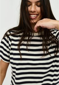 Striped t-shirt featuring navy blue and cream stripes, with a round neckline and short sleeves, made of soft fabric.