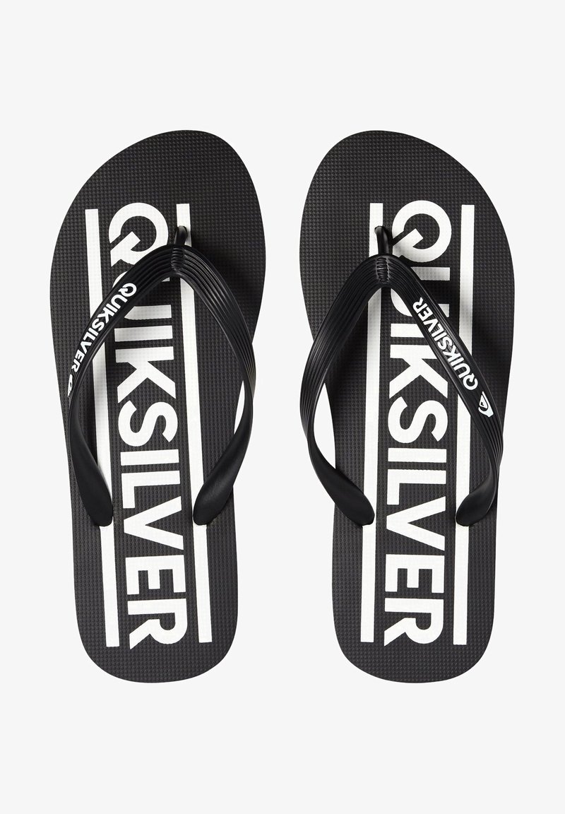 Black flip-flops with a textured surface, featuring black thong straps and white "Quiksilver" branding on the insole, set against a contrasting backdrop.