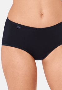 Culotte haute en mélange de coton noir avec une texture lisse, une ceinture élastique étroite et une petite étiquette logo sur le côté gauche à l'avant.