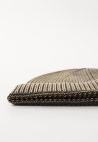 Beanie tricotat maro cu nervuri verticale, având un tiv pliant și o textură moale. Materialul este ușor și durabil.