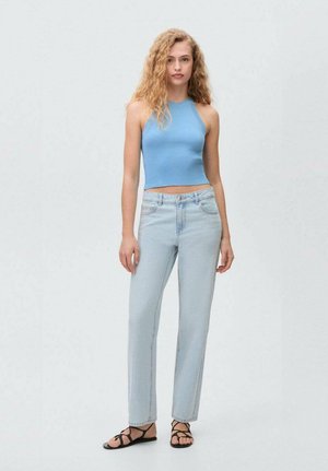 Ljusblå ribbad crop top, högmidjade ljusa jeans och svarta platta sandaler. Modellen står med avslappnade armar och vänder sig framåt mot en neutral bakgrund.