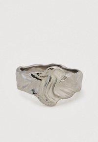 Srebrn prstan z izbočeno abstraktno obliko, ki vključuje tekoče, organske oblike in gladko, polirano površino.