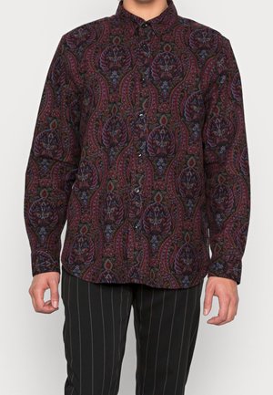 Chemise à manches longues à boutons en tissu foncé avec un motif paisley dans des teintes de rouge, violet et vert. Boutons noirs et poignets ajustables.