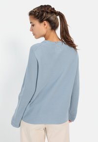 Lichtblauwe ribgebreide trui met lange mouwen en een ronde halslijn, met een subtiele naad op de rug en een relaxte fit.