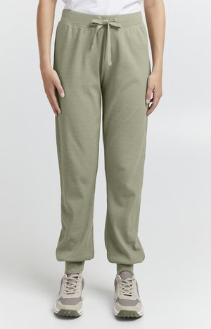 Lys grønne bomullssweatpants med snor i livet, avsmalnende mansjetter og sidelommer. Kombinert med nøytrale joggesko.