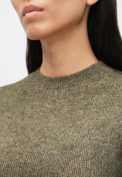 Olivovo zelený pletený sveter s patentovaným okrúhlym výstrihom a textúrovanou tkaninou. Záber zblízka ukazujúci detaily stehov a tvar.