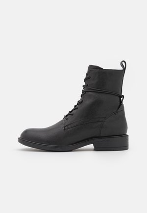 Stivali alla caviglia in pelle nera con punta rotonda, lacci frontali e linguetta sul retro. Superficie tessurizzata e dettaglio del tacco piatto.