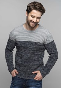 Maglione lavorato a maglia con design a righe orizzontali in grigio e blu scuro, con una finitura testurizzata e un piccolo logo sul petto. Maniche lunghe.