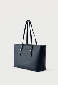 Laivastonsininen nahkainen olkalaukku, jossa kaksi pitkää kahvaa, teksturoitu pinta, hopeanväriset metalliosat ja etutasku.