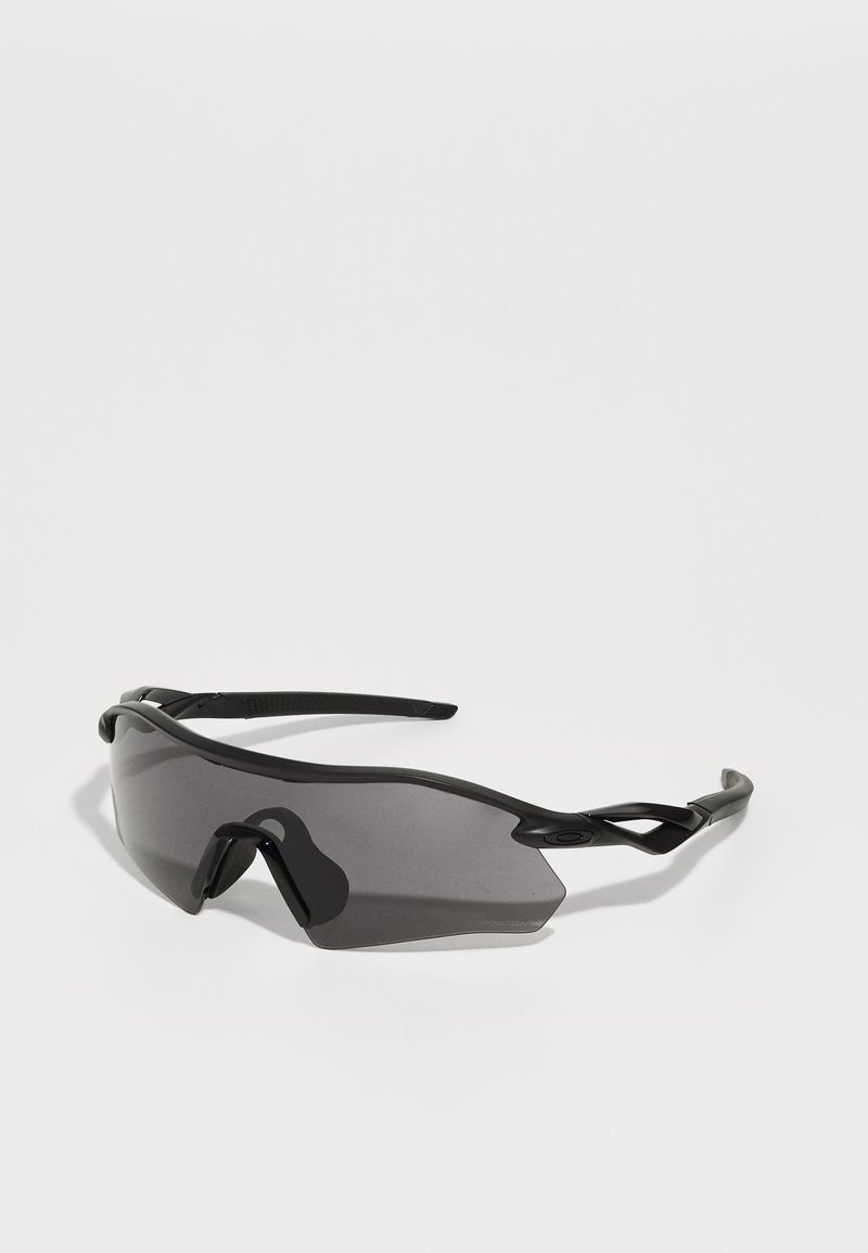 Sports sunglasses with a full wrap-around black plastic frame, dark tinted lenses, and distinctive angular design. Flexible ear arms for comfort.