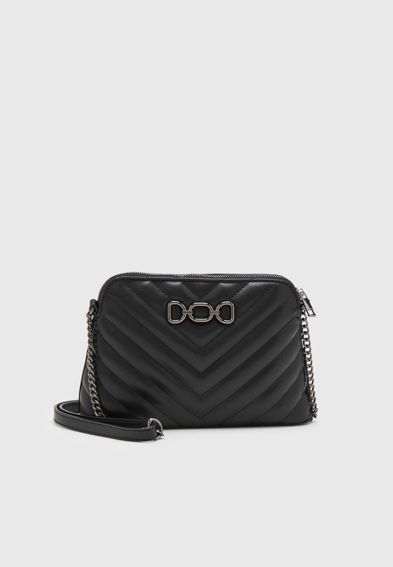 Překládaná černá kožená kabelka přes rameno s chevron vzorem, stříbrným řetízkem a výrazným logem řetězu na přední straně. Uzavírání na zip.