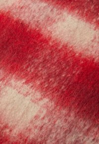 Villane tekk pehme tekstuuriga, millel on punase ja kreemika ruudulise mustriga. Pind näeb veidi karvane välja koos segatud värvidega.