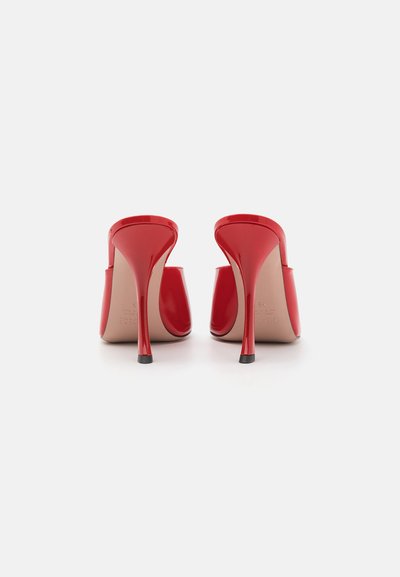 Red patent leather high-heeled mules with a sleek design, pointed toe, and a slim stiletto heel. Smooth texture and minimalist style.