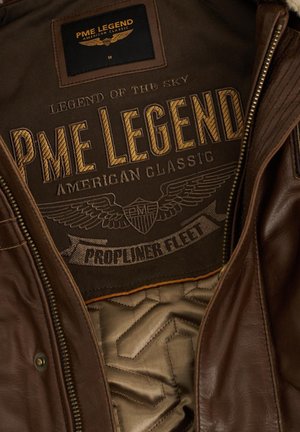 Unutrašnjost smešnog kožnog jakna sa pamučnom podlogom. Značajno brendiranje izvezeno u zlatnoj i crnoj boji, sa krilima i natpisom "PME Legend."