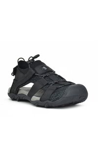 Sandalias negras con un diseño de malla transpirable, suela de goma, cordones ajustables de bungee y puntera reforzada para mayor protección.