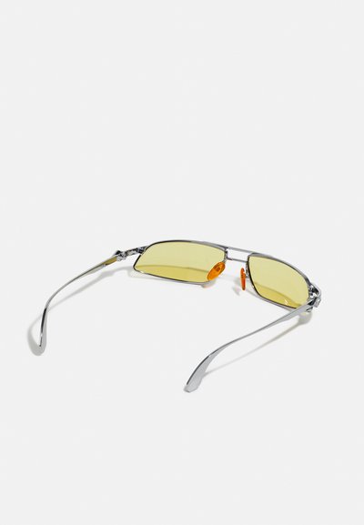 Metal sunglasses with yellow lenses, silver frame, and orange nose pads. Slim, angular design with curved arms. Lightweight and modern style.